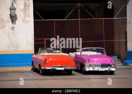 HAVANNA, KUBA - 30. MÄRZ 2017: Zwei konvertible amerikanische Oldtimer aus den 60er Jahren parkten am Eingang einer Garage in der Stadt Havanna, Kuba. Stockfoto