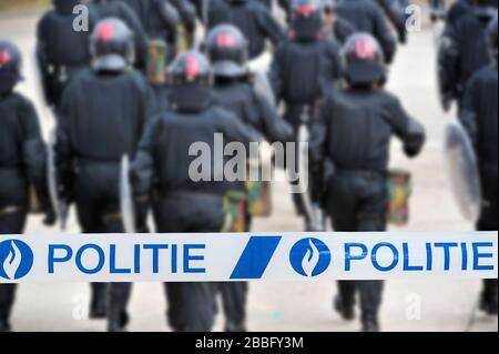 Polite/Polizeiband vor der belgischen Bereitschaftstruppe, die in Belgien eine Schutzbarriere mit Bereitschaftssiegen bildet Stockfoto