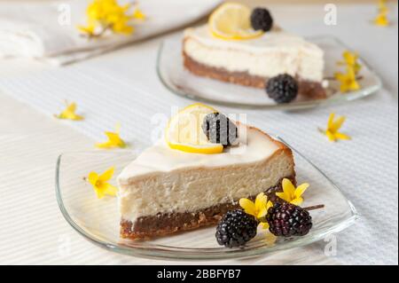 Zwei Zitronenscheiben mit graham-cracker-Kruste, die mit Brombeeren, Zitronenscheiben und Forsythie-Blumen verziert sind. Stockfoto