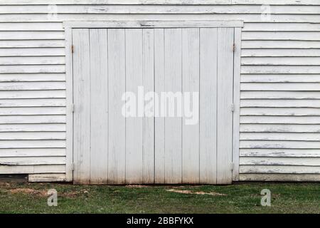 Ein blasser weißer Holzhausbau, Tür und Gras Stockfoto