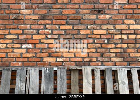 Eine alte, rote Ziegelwand mit gewitterten Paletten Stockfoto