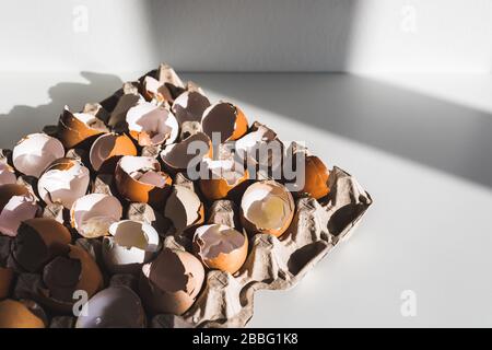 Haufen zerbrochener leerer Eggshell im Karton auf weißem Tisch. Kochen auf osterkonzept. Ungewöhnliches Foto von Eiern. Stockfoto