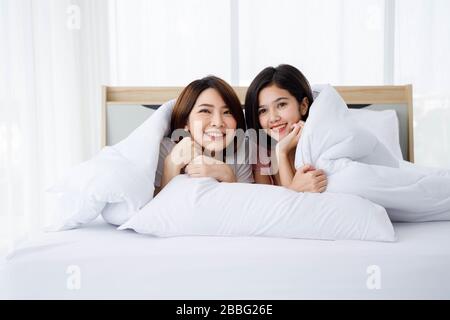 Zwei asiatische Frauen legen sich gemeinsam auf das Bett. Porträt des thailändischen Ehepaares im Schlafzimmer. Stockfoto