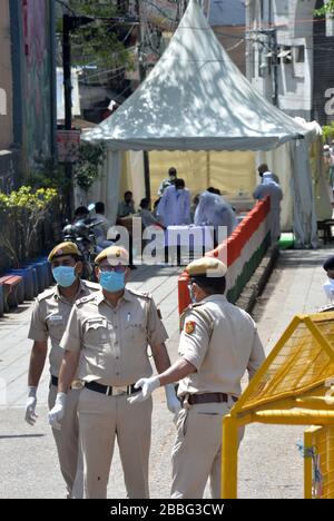 Delhi-Polizisten, die Gesichtsmasken tragen, stehen an einer Barrikade, um zu verhindern, dass jemand die Kontrolle in einem provisorischen medizinischen Lager ausatme, das außerhalb des Hauptquartiers von eingerichtet wurde Stockfoto