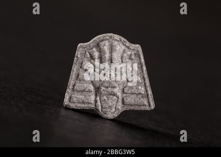 Pharao Ecstasy-Pille auf schwarzem Hintergrund. MDMA-unterstützte Psychotherapie. Stockfoto