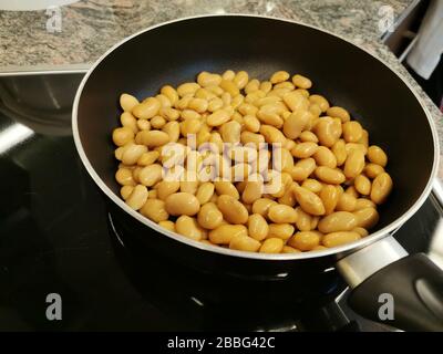 Kochen - gelbe Bohnen werden in einer Bratpfanne gebraten Stockfoto
