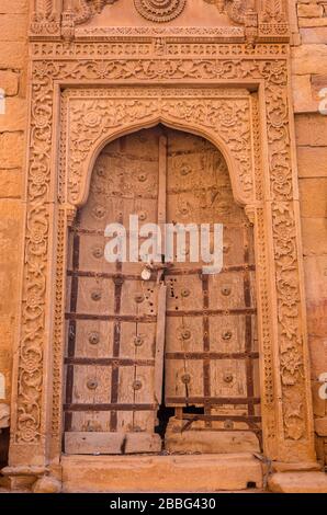 Schöne Schnitzdetails an der Rahmenpforte aus gelbem Sandstein und verlassene alte Haustür in Jaisalmer, Rajasthan, Indien. Stockfoto