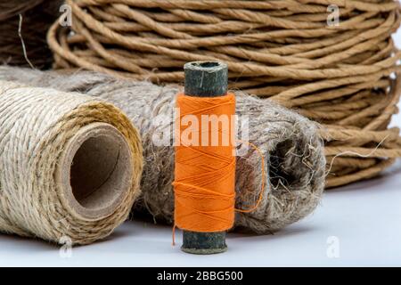 Abbildung: Schieber mit orangefarbenem Gewinde auf dem Hintergrund von grobem Garn Stockfoto