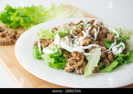 Klassischer Caesar-Salat mit seinen Zutaten: Gegrilltes Hähnchen, Croutons, Salat und Sauce Stockfoto