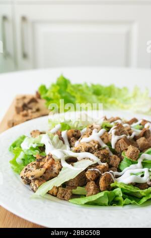 Klassischer Caesar-Salat mit seinen Zutaten: Gegrilltes Hähnchen, Croutons, Salat und Sauce Stockfoto