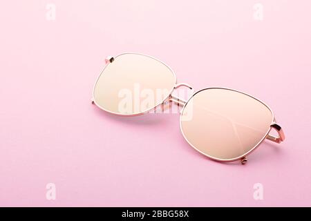 Classic Aviator Spiegel-Sonnenbrille mit goldenem Metallrahmen im Nahaufnahme auf pinkfarbenem Hintergrund, Draufsicht Stockfoto