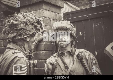 Freunde lächeln, junge Männer miteinander in Kostümen als amerikanische US-Soldaten plaudern, Sommerveranstaltung der 1940er Jahre, Black Country Living Museum, Großbritannien. Stockfoto