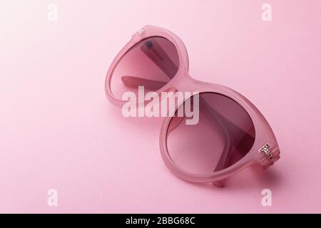 Klassische, ovale, überdimensionale Sonnenbrille in Pink auf dem Hintergrund, Draufsicht. Trendige Retro-Farben Stockfoto