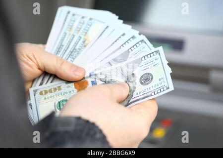 Männliche Hände, die Fantail von Hundert Dollar-Banknoten am geldautomaten halten Stockfoto