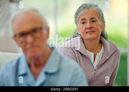 Besorgt ältere Frau, die ihren kranken Ehemann betrachtet. Stockfoto