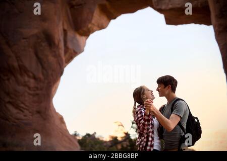 Fröhliches junges Paar tanzt nahe beieinander während der Wanderung in der Wüste Stockfoto