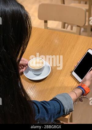 Mädchen hält eine Tasse Kaffee auf einem Holztisch im Café, Panama-Stadt, Mittelamerika Stockfoto