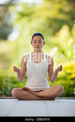 Entspannte junge Frau meditiert auf einem Deck Stockfoto