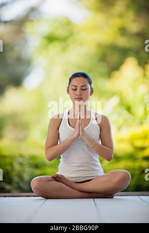 Entspannte junge Frau meditiert auf einem Deck Stockfoto