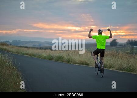 Reifer Mann, der auf einer Landstraße mit dem Fahrrad unterwegs ist Stockfoto