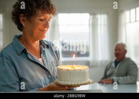 Glücklich reife Frau hält einen Geburtstagskuchen Stockfoto