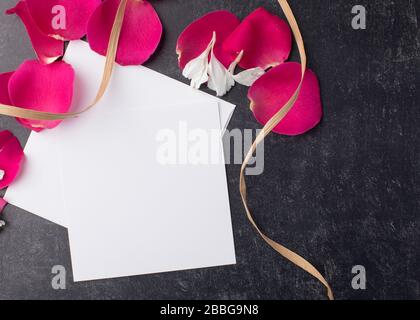 Rote Rosenblätter mit einem Raffia-Band und einer leeren Karte machen eine noble Party Einladung Stockfoto