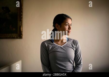 Porträt einer jungen Frau, die im Innenbereich gedanklich in die Ferne blickt Stockfoto
