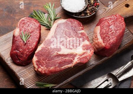 Auswahl an frischen rohen Rindersteaks mit Gewürzen auf dem Schneidebrett Stockfoto