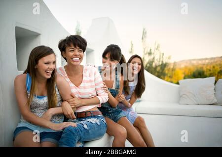 Vier lächelnde Freunde sitzen auf einem Balkon Stockfoto