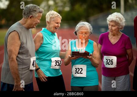 Gerne ältere Freunde feiern Geburtstag vor einem Leichtathletik Veranstaltung. Stockfoto