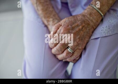 Die Hände einer älteren Frau klafften in ihrem Schoß Stockfoto