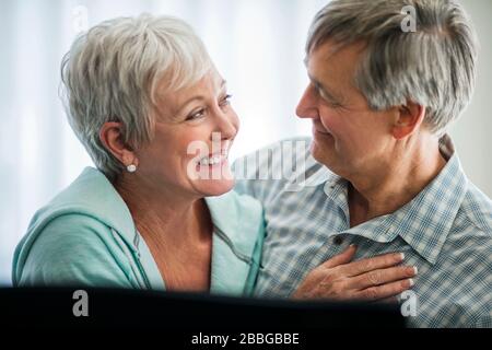 Liebevoll reifes Paar lächelt, während sie in die Augen des anderen blicken Stockfoto