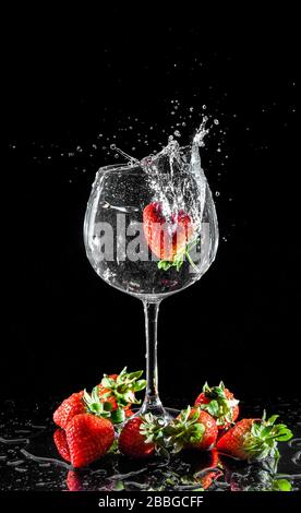 Erdbeere spritzt in Wasser Stockfoto