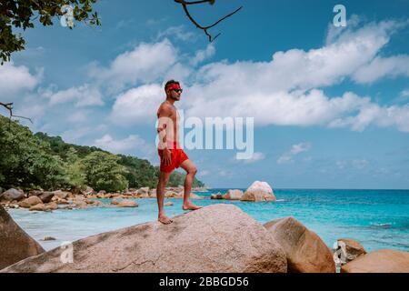 Cote D'Or Beach, Praslin Seychelles Tropical Island, junge Männer schwimmen kurz am weißen Strand mit riesigen Felsbrocken und Felsen und einem weißen tropischen Stockfoto