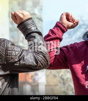 Ein Ellenbogen. Ein neuer Gruß, um die Ausbreitung des Coronavirus zu vermeiden, wenn sich zwei Freunde mit ungeschützten Händen auf der Straße treffen Stockfoto