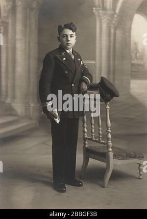 fotoporträt des studios holy Communio um 1920 eines kleinen Jungen, der die bibel vor der christlichen Kircheninnenkulisse in Belgien hält Stockfoto