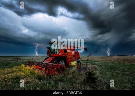 Sturm mit Blitzschlag im Hintergrund mit einem alten Traktor im Vordergrund in den ländlichen Kansas Vereinigten Staaten Stockfoto