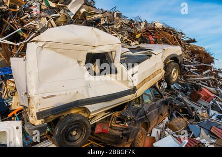 Riesiger Berg mit hauptsächlich Metallmüll, Geräten und einem Paar Autos in einem Schrottplatz. Stockfoto