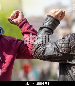 Ein Ellenbogen. Ein neuer Gruß, um die Ausbreitung des Coronavirus zu vermeiden, wenn sich zwei Freunde mit ungeschützten Händen auf der Straße treffen Stockfoto