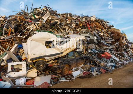 Riesiger Berg mit hauptsächlich Metallmüll, Geräten und einem Paar Autos in einem Schrottplatz. Stockfoto