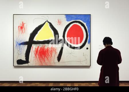 Besucher vor dem Gemälde des spanischen Modernistenmalers Joan Miró mit dem Titel "Figur vor der Sonne" (1968), das in der Fundació Joan Miró (Joan Miró Foundation) in Barcelona, Katalonien, Spanien ausgestellt ist. Stockfoto