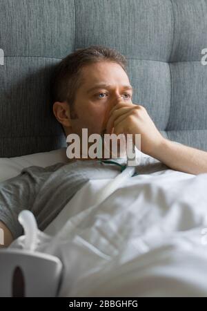 Kranker Mann mit Inhalatormaske auf dem Gesicht im Bett. Konzept zur Vorbeugung von Coronavirus. Stockfoto