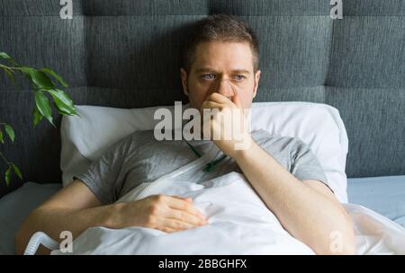 Kranker Mann mit Inhalatormaske auf dem Gesicht im Bett. Konzept zur Vorbeugung von Coronavirus. Stockfoto