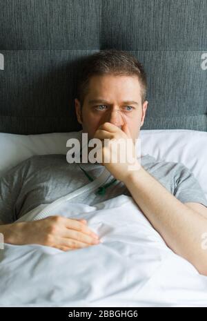 Kranker Mann mit Inhalatormaske auf dem Gesicht im Bett. Konzept zur Vorbeugung von Coronavirus. Stockfoto