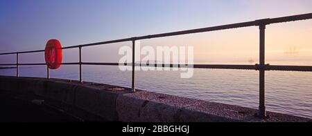 Guernsey. St. Peter Port. Blick auf den Sonnenaufgang durch Geländer mit Rettungsschwimmfrisel. Stockfoto