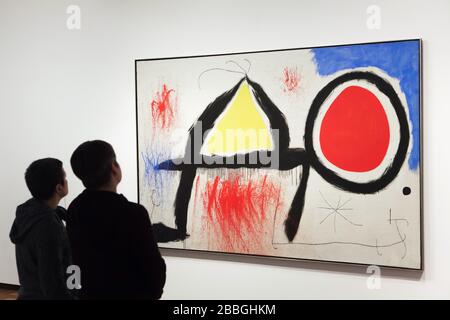 Besucher vor dem Gemälde des spanischen Modernisten Malers Joan Miró mit dem Titel "Figur vor der Sonne" (1968), das in der Fundació Joan Miró (Joan Miró Stiftung) in Barcelona, Katalonien, Spanien ausgestellt ist. Stockfoto