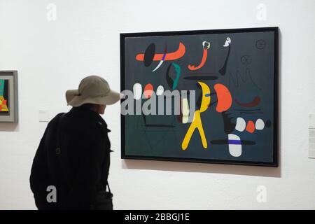 Besucher vor dem Gemälde des spanischen Modernistenmalers Joan Miró mit dem Titel "Malerei" (1933), das in der Fundació Joan Miró (Joan Miró-Stiftung) in Barcelona, Katalonien, Spanien ausgestellt wurde. Stockfoto