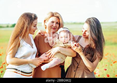 Drei Generationen. Großmutter, Töchter und Enkelin auf einer grünen Wiese. Stockfoto