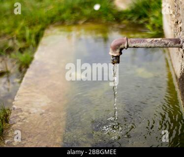 Kostenloser Wasserbrunnen für die Menschen in die Wildnis. Wasserhähne sind zu alt, wahrscheinlich aus dem achtzehnten Jahrhundert. Es gibt Kreise auf Wassertank. Stockfoto