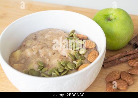Gesundes Frühstück: Haferbrei mit Zimt, apfel und Banane mit Mandeln und Kürbiskernen Stockfoto